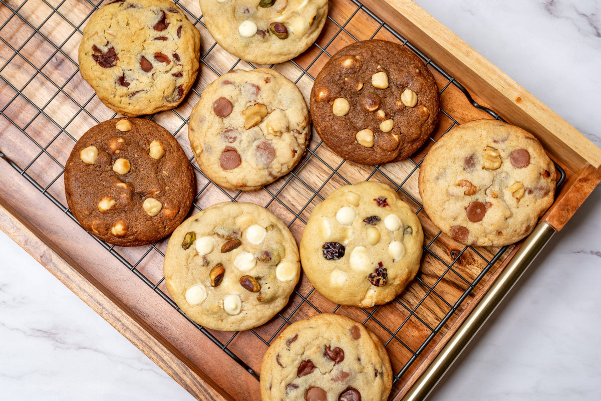 Assorted gourmet cookies featuring a variety of flavors and textures, including classic chocolate chip, pistachio cookie, coffee cookie, hazelnut cookie, macadamia and white chocolate cookie, oats and dark chocolate cookie, walnut milk chocolate cookie, perfect for any sweet craving