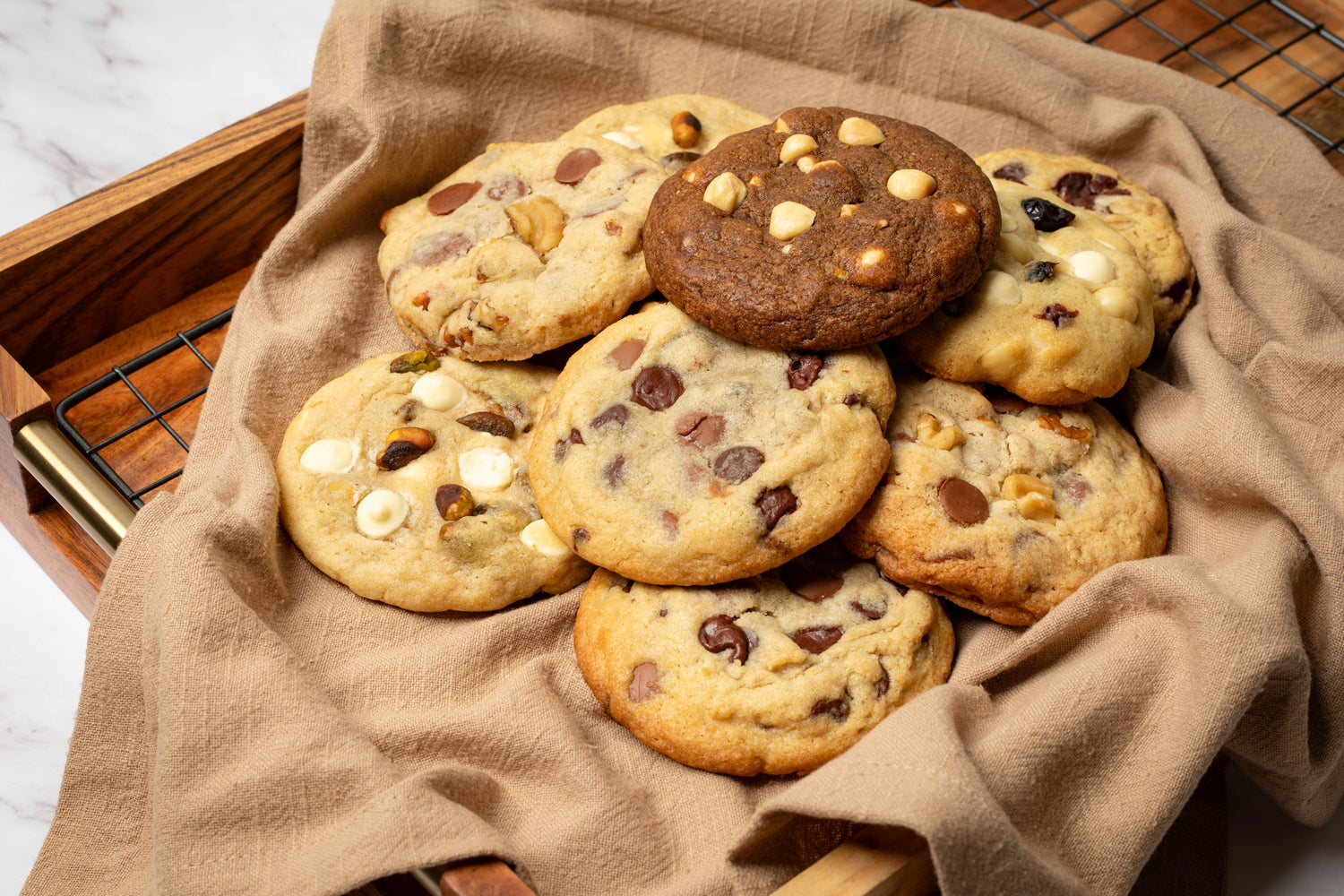 Assorted gourmet cookies featuring a variety of flavors and textures, including classic chocolate chip, pistachio cookie, coffee cookie, hazelnut cookie, macadamia and white chocolate cookie, oats and dark chocolate cookie, walnut milk chocolate cookie, perfect for any sweet craving