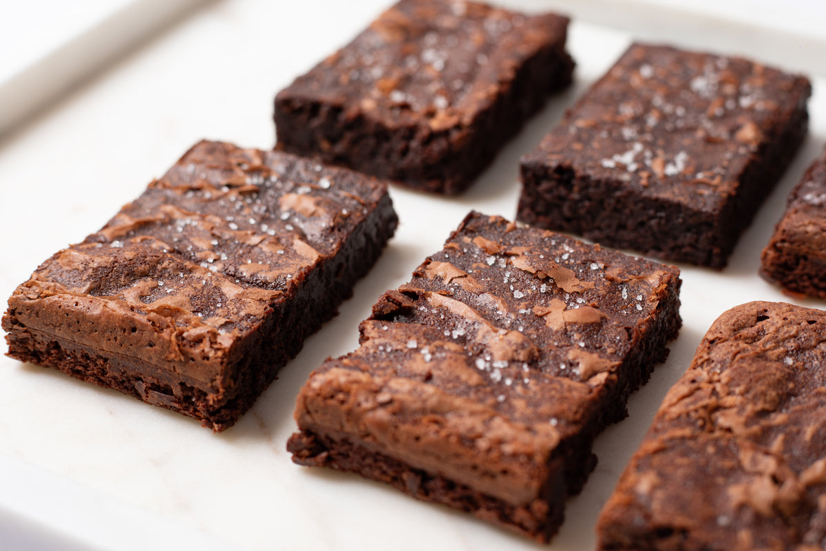 Decadent fudge brownies topped with delicate Fleur de Sel sea salt from France, adding a refined touch of savory contrast to the rich, chocolatey sweetness