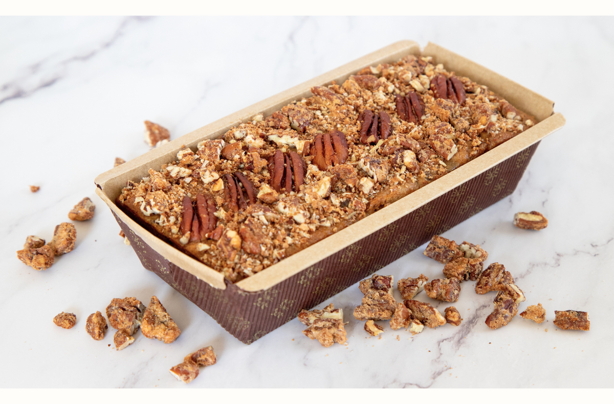 Decadent fruitcake infused with rum and loaded with dates, raisins, cranberries, walnuts, and praline pecans, delivering a perfect balance of rich, fruity sweetness and nutty crunch