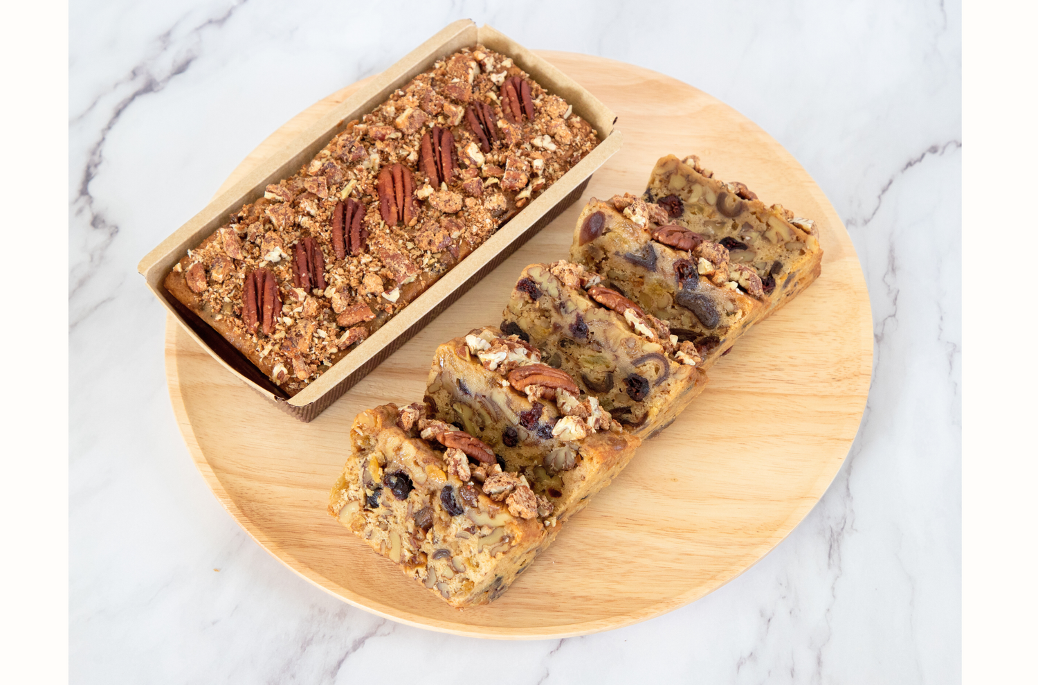 Classic holiday fruitcake infused with rum, packed with dates, raisins, cranberries, walnuts, and praline pecans for a rich, moist, and flavorful indulgence.