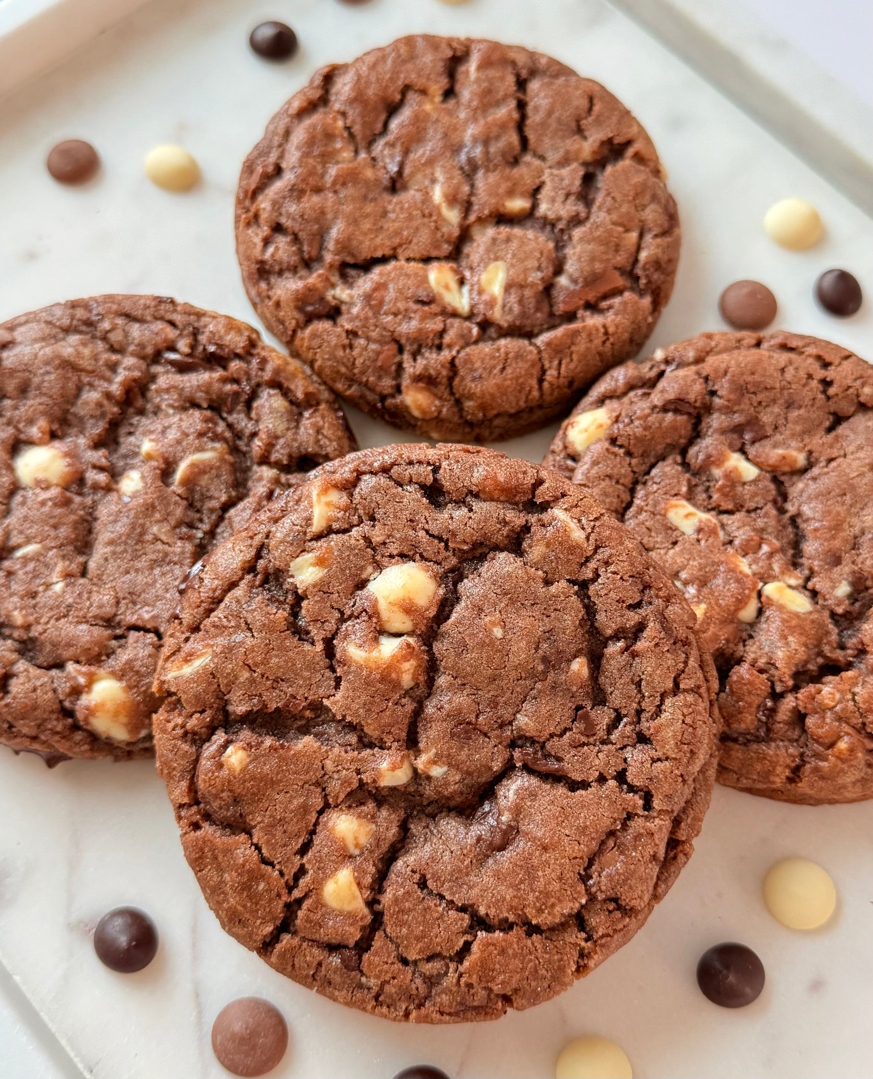 Chocolate cookies with white and brown chips on a marble surface