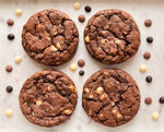 Four chocolate cookies with chocolate chips on a marble surface