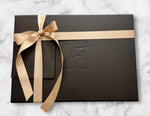 Luxury black gift box with gold ribbon and logo on a marble surface